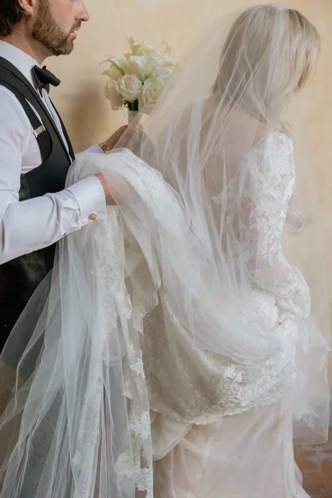 detail of a man carrying a piece of a bride veil