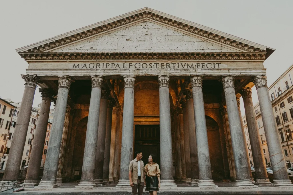 a couple is walking in front of the Pantheon in Rome