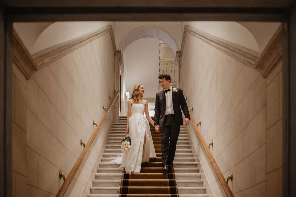 a wedding couple is walking down the stairs at Marriott Hotel Flora in Rome
