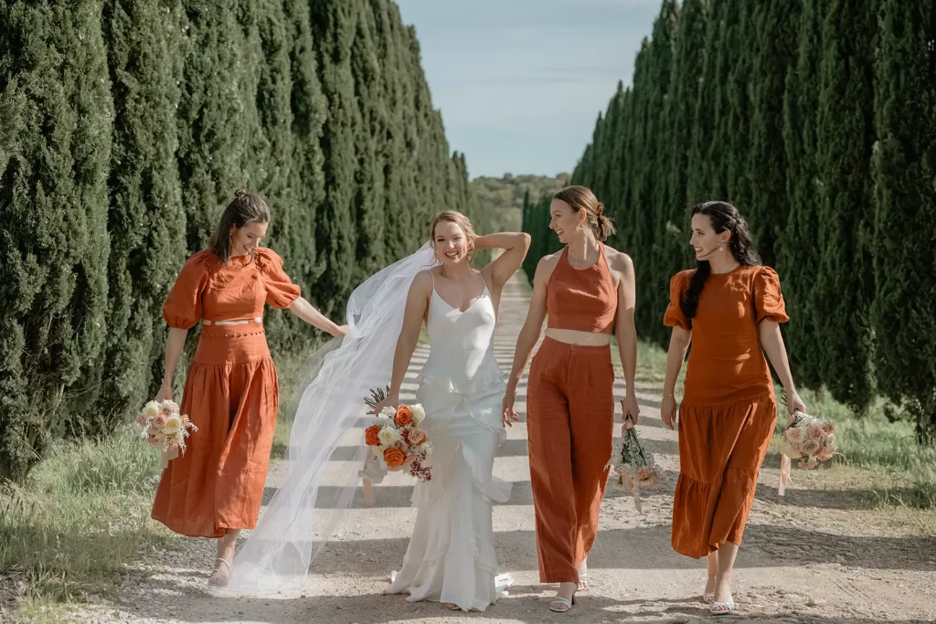 Bridesmaids are walking in a tuscan countryside alley