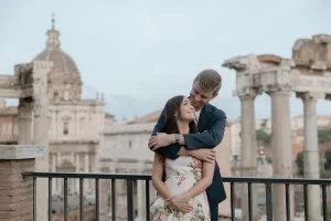 a couple is hugging each other with roman forums in the background