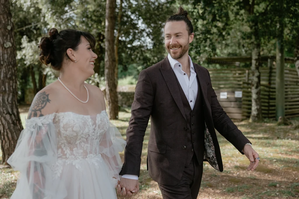 a newlywed couple is walking holding hands and smiling at each other