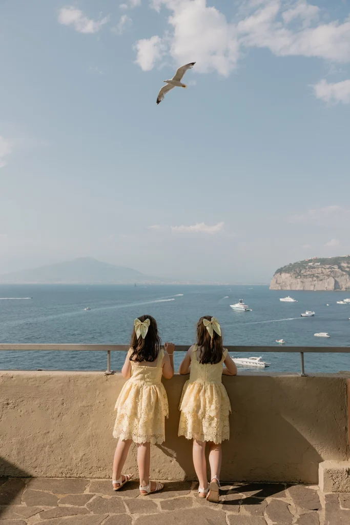 two little girls are watching the sea from a balcony in Sorrento