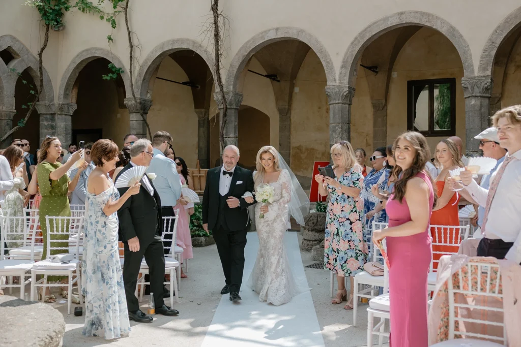 a bride is walking down the aisle in Chiostro San Francisco in Sorrento