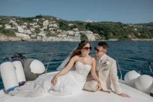 a couple of newlywed is on a boat in Amalfi coast, they are smiling
