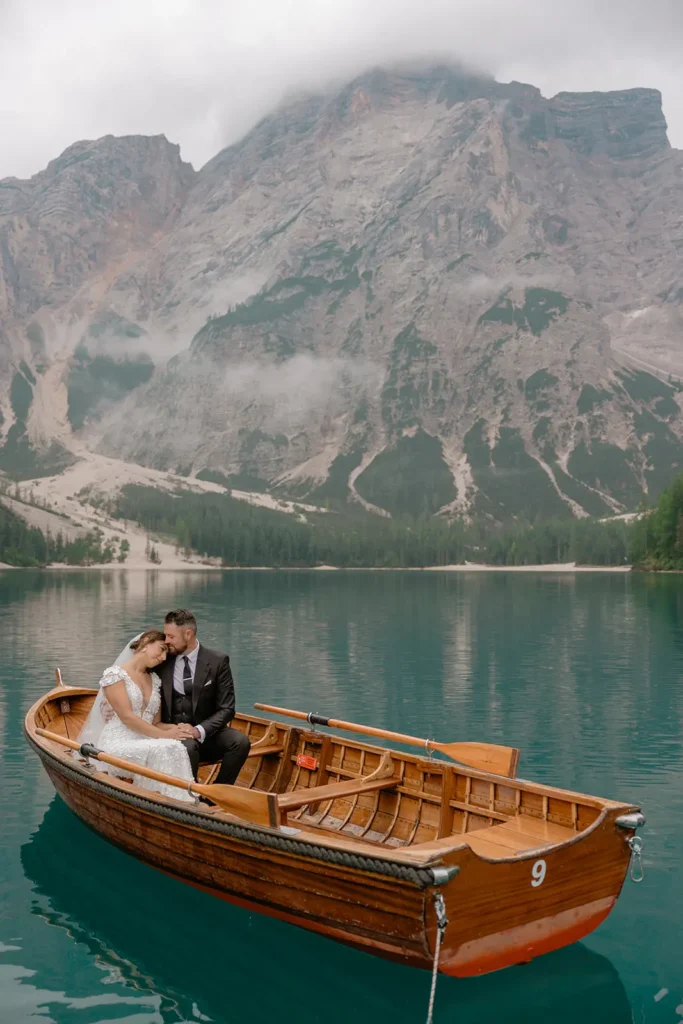 a wedding couple is in a woodboat in Lake Braies Dolomites by Cristiana Fiorini