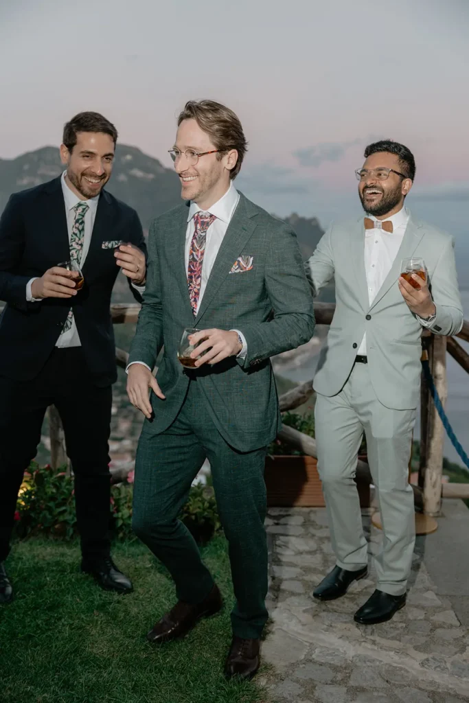 3 guys are laughing with sea views in the background