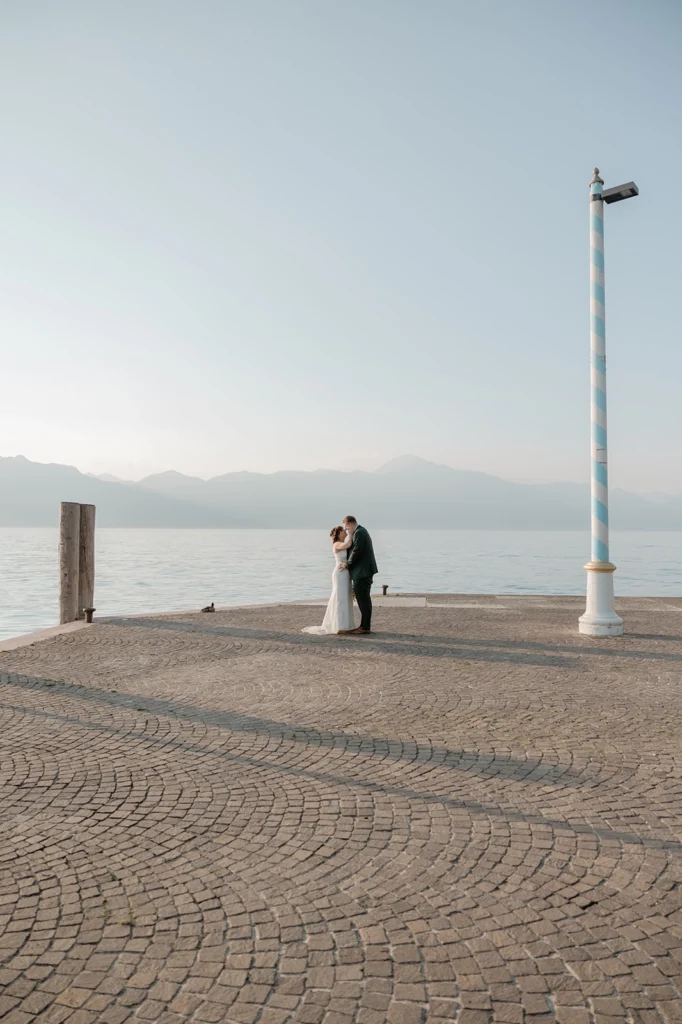 a newlywed couple is looking at each other on Lake Garda shores