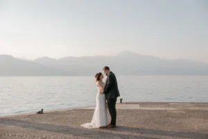 a newlywed couple is looking at each other on Lake Garda shores